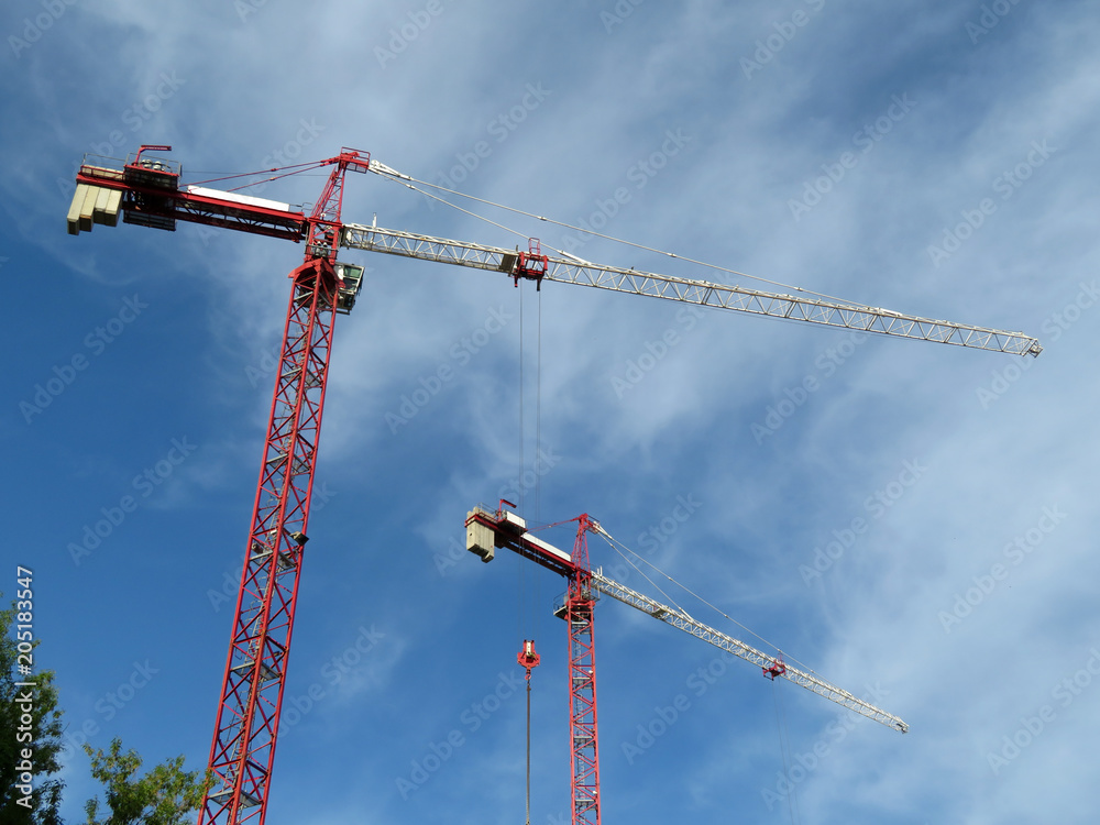 Construction cranes on cloudy blue sky background Construction cranes on cloudy blue sky background