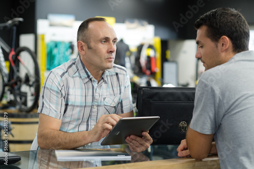 Obraz na plátně bicycle store seller using digital tablet to fill clients order