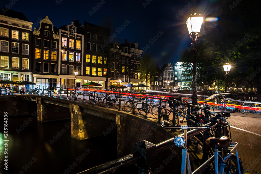 Night view with bridge, bicycles and water reflection in Amsterdam city, Netherlands