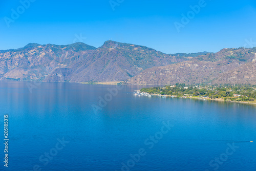 View from Lake Atitlan in the early morning, blue skys and clear water, beautiful magic lake with volcanos and indigenous people in the highland of Guatemala  © Simon Dannhauer