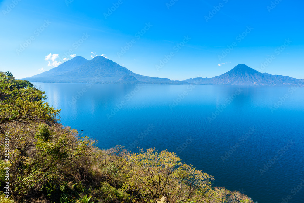 View from Lake Atitlan in the early morning, blue skys and clear water, beautiful magic lake with volcanos and indigenous people in the highland of Guatemala 