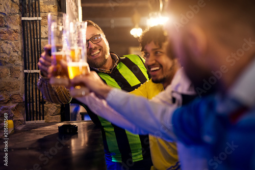 Soccer fans are sitting at the counter in the pub and are having a deep and friendly conversation about whose team is better, while drinking draft beer. © dusanpetkovic1