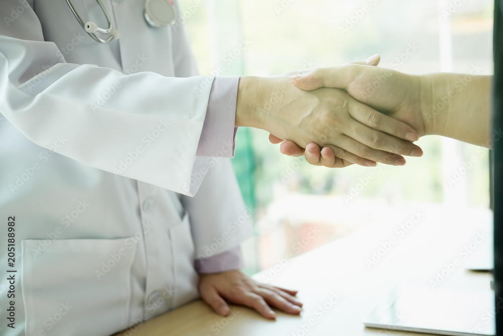 doctor handshake with a patient at doctors bright modern office in hospital, healthcare and professionalism concept doctor handshake with a patient at doctors bright modern office in hospital, healthcare and professionalism concept