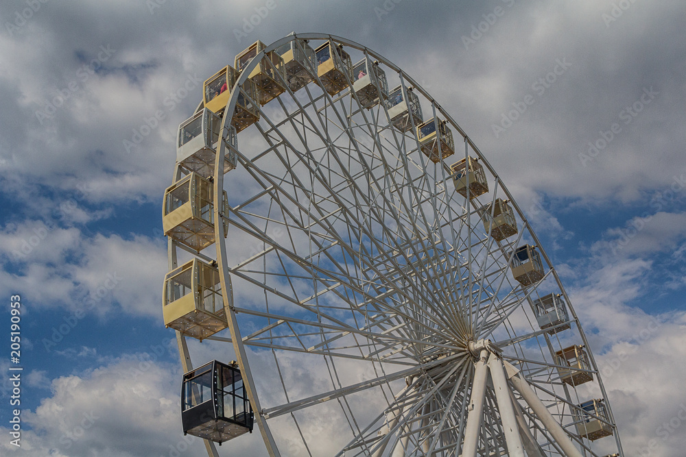 Ferris wheel on background cloudy sky. Festival