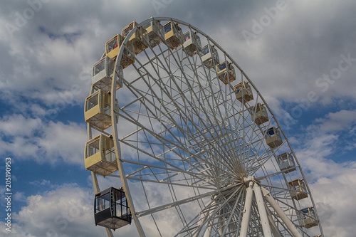 Ferris wheel on background cloudy sky. Festival
