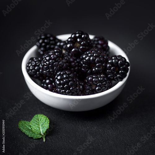 Closeup of fresh blackberries in a white bowl  on black textured  background