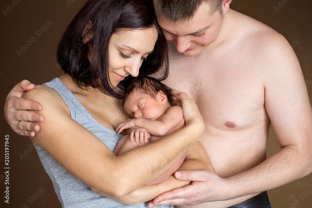 Beautiful mother and father smiling holding their newborn baby Beautiful mother and father smiling holding their newborn baby