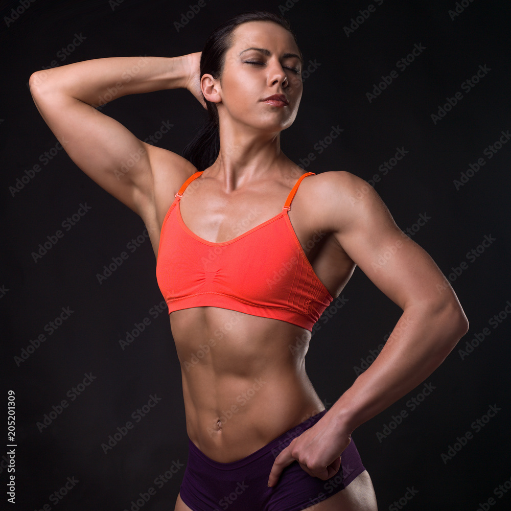 Girl. Fitness model in an orange top, on a black background. Girl. Fitness model in an orange top, on a black background.