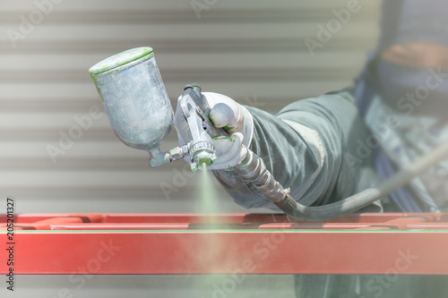 Workers spraying paint on metal work.