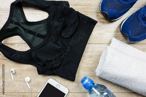 Fitness activity concept - flat lay of some personal sport accessories for woman on a wooden background.