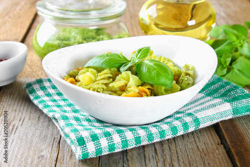 Pasta with pesto sauce on an old wooden table.