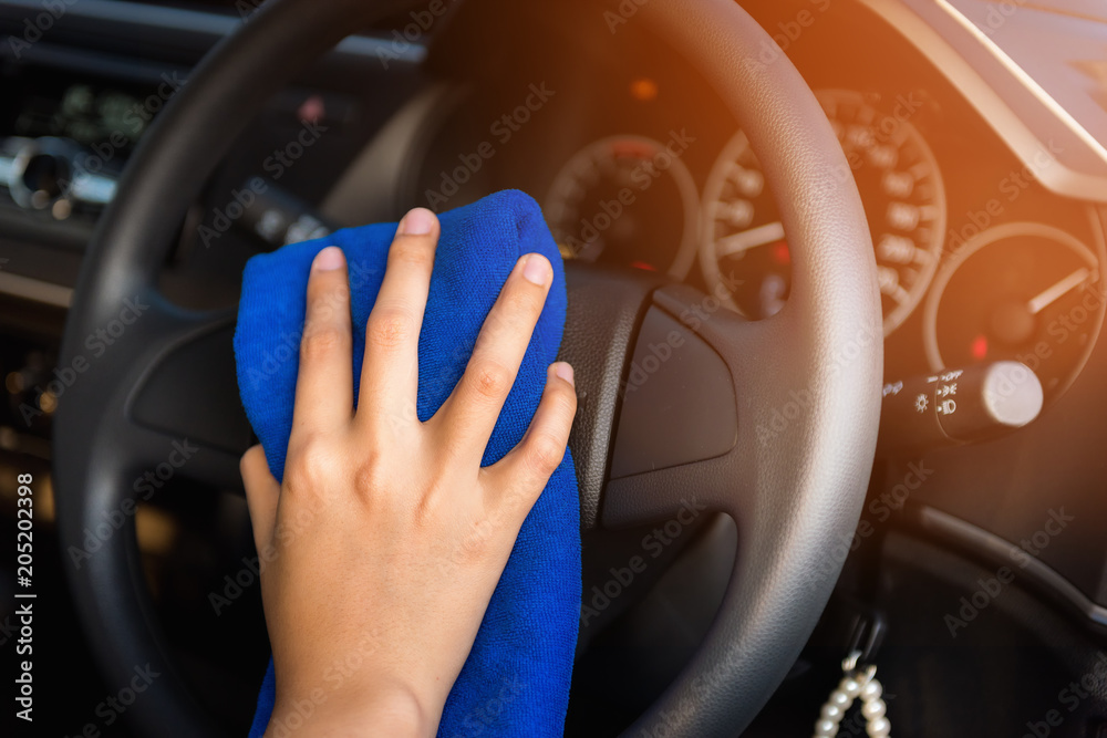 Close-Up of Woman Hand is Cleaning Car Steering Wheel With Cleaner Microfiber Cloth, Car Washing and Vehicle Maintenance Service. Business Cars Wash and Transportation Automotive Equipment