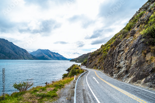 The stunning landscape of road beside the ocean with a cloudy and mountain scene.