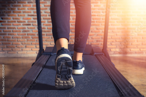 Foto Close up on legs athlete, Woman running in a gym on a treadmill