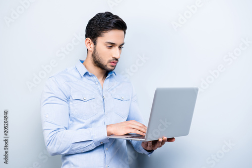 Portrait of attractive hardworking person with black hair texting on keypad keyboard using wi-fi internet on laptop checking email making blog online shopping isolated on grey background