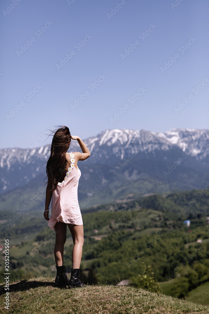 A beautiful woman in the dress enjoys the view of a mountain landscape