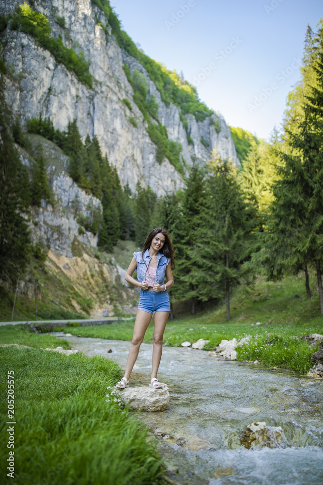 Naklejka premium A beautiful tourist enjoys nature next to a mountain river