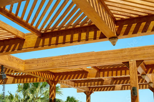 Part of the wooden roof structure on the gazebo on blue sky background