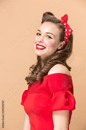 Beautiful young woman with pinup make-up and hairstyle. Studio shot on pastel background