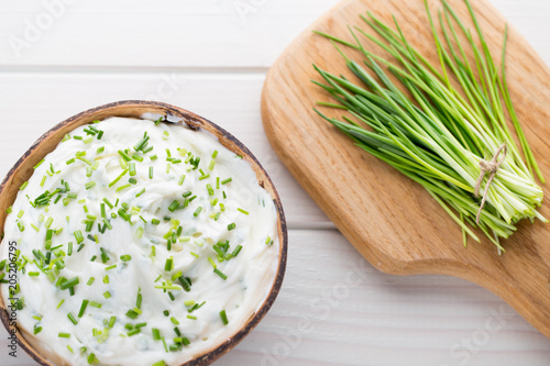 Bowl of cream cheese with green onions  dip sauce on wooden table.
