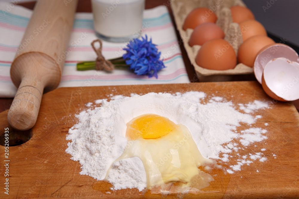 pizza or pie recipe ingridients, food flat lay on wood kitchen table background. baking ingredients. Bowl, eggs, milk, flour, eggbeater, rolling pin and eggshells pizza or pie recipe ingridients, food flat lay on wood kitchen table background. baking ingredients. Bowl, eggs, milk, flour, eggbeater, rolling pin and eggshells