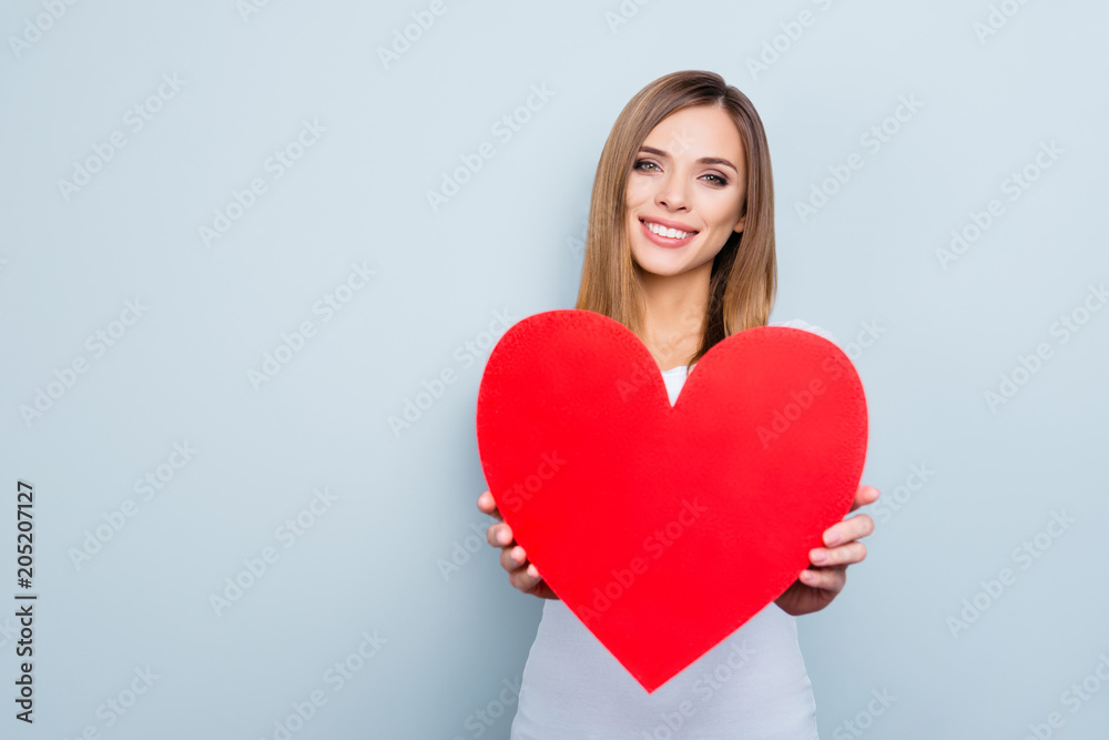 Portrait with copy space, empty place of lovely cute girl holding big red heart looking at camera isolated on grey background. Advertisement concept Portrait with copy space, empty place of lovely cute girl holding big red heart looking at camera isolated on grey background. Advertisement concept
