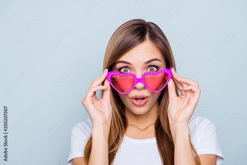 Portrait of shocked frustrated girl looking out pink glasses in heart shape with wide open eyes mouth isolated on grey background Portrait of shocked frustrated girl looking out pink glasses in heart shape with wide open eyes mouth isolated on grey background