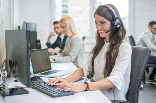 Obraz na płótnie Attractive young woman working at call center office with her colleagues