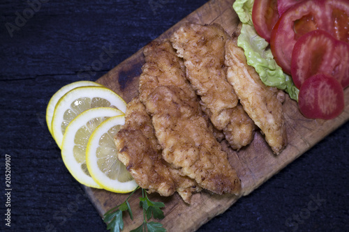 Breaded Chicken Meat With Salad And Lemon Resting On a Rustic Wooden Board photo