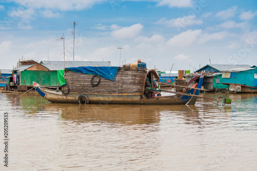 Photo A sampan-like boat, including a small shelter with a curved roof made of wood and thatch that might be a permanent habitation, is anchored in Cambodia's floating village Chong Kneas on Tonle Sap Lake