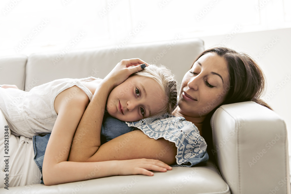 Portrait of beautiful mother and her little daughter sitting together on couch Portrait of beautiful mother and her little daughter sitting together on couch