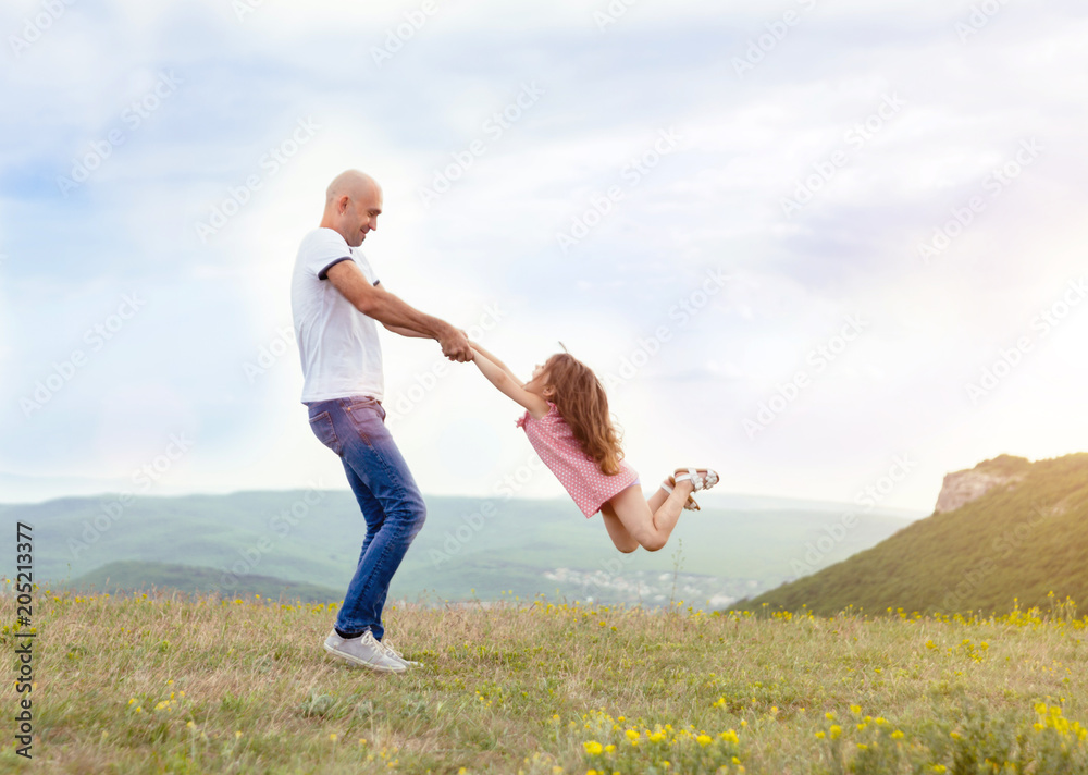 Fototapeta premium Father playing with his daughter in sunny field