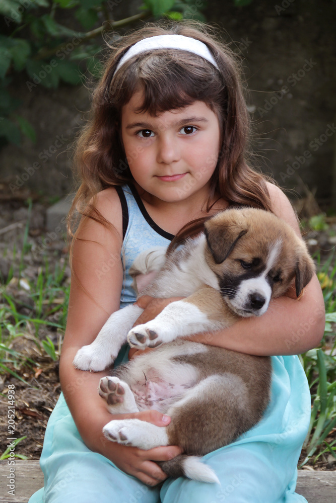 Mädchen sitzt im Garten hält Hund Welpe American Akita Mix