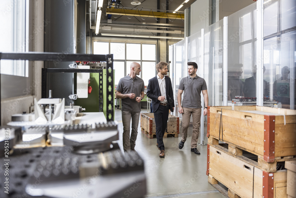 Three men walking and talking in factory Three men walking and talking in factory