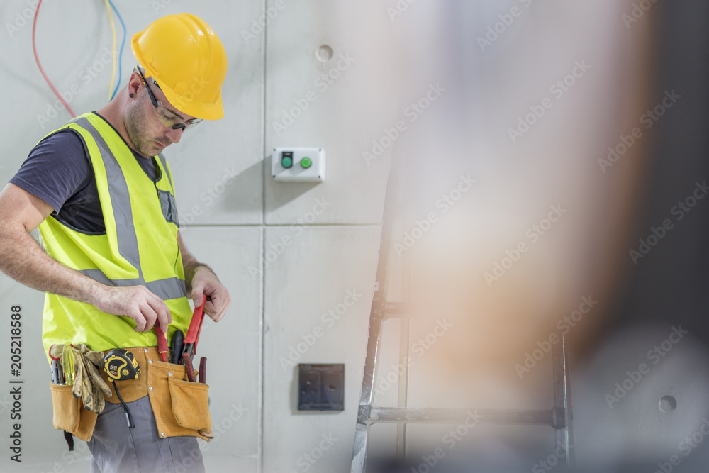 Electrician taking tools out of belt on construction site Electrician taking tools out of belt on construction site