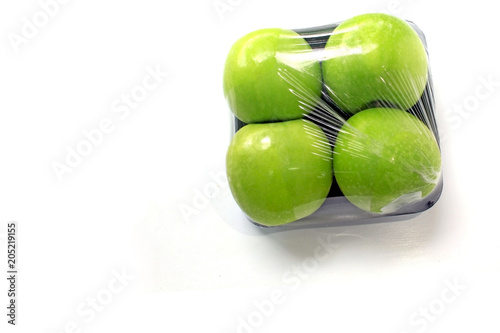 Apple is wrapped in clear plastic on a white background, leaving space.