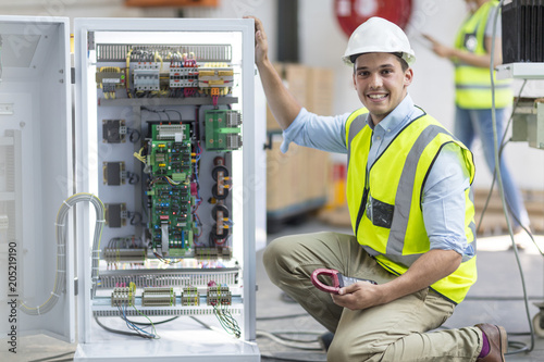Portrait of smiling technician working on a box with circuit boards