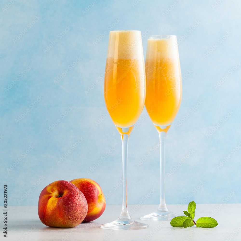 two glasses of champagne with a cocktail of Bellini and fresh peaches on a blue background. summer refreshing drink