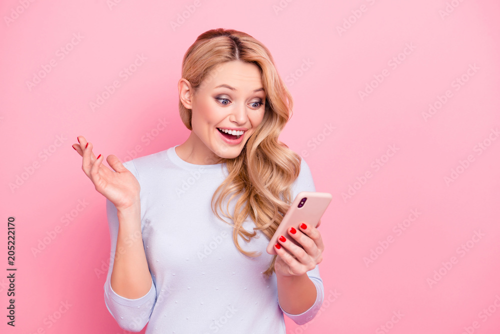 Portrait of wondered woman, excited student, shocked girlfriend having smart phone cellphone in hands watching picture video reading news isolated on pink background Portrait of wondered woman, excited student, shocked girlfriend having smart phone cellphone in hands watching picture video reading news isolated on pink background