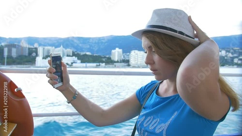 Woman in hat makes selfie bay with yachts. Background is the town of Cremea photo