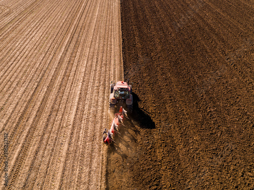 фотографія Aerial shot of a farmer plowing stubble field