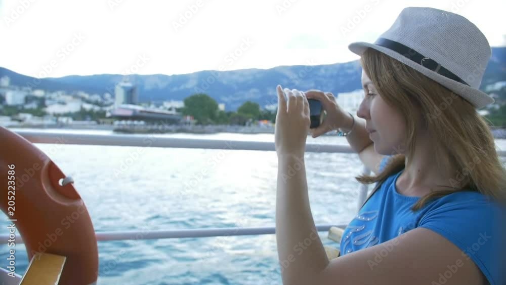 Woman in hat makes selfie bay with yachts. Background is the town of Cremea Woman in hat makes selfie bay with yachts. Background is the town of Cremea