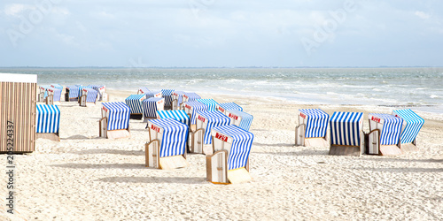 Tableau sur toile Viele blau-weiss gestreifte Strandkörbe am Meer