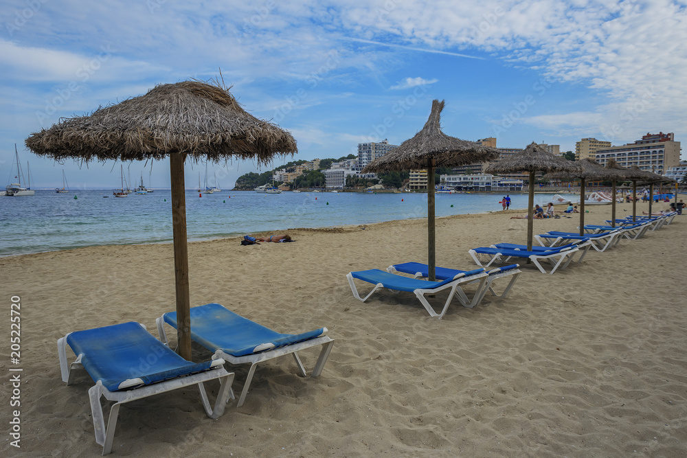 view of the sandy beach with sun loungers and umbrellas against the blue sky