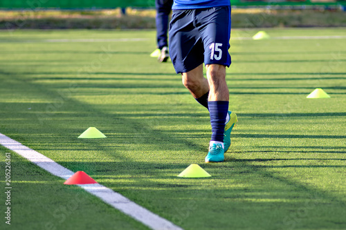 Soccer football players during the team training before the match. Exercises for football soccer youth team. Player exercises with ball and marker cones