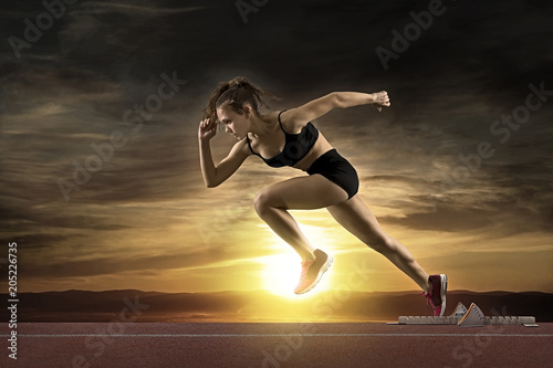 Kobieta sprinter pozostawiając bloki startowe na torze sportowym