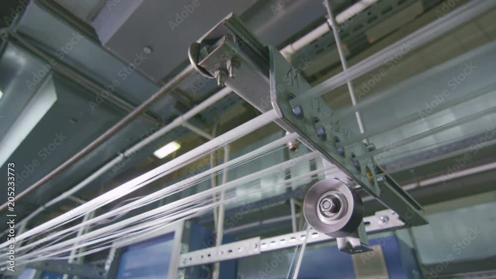 closeup glass threads stretch through holes to loom
