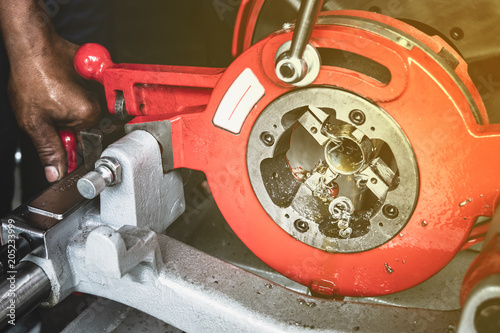 the worker use  pipe threading machinesteel in industrial shop.