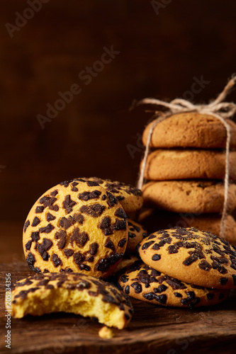 Sweet assortment of biscuits on a round wood log over rustic wooden background, close-up, selective focus. © Aleksey