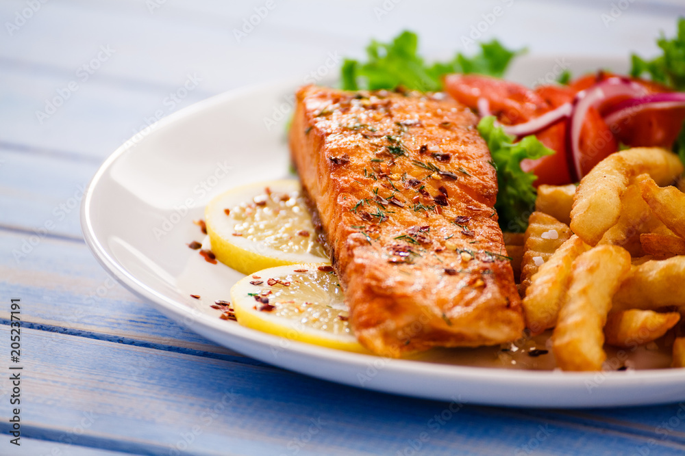 Fried salmon with french fries on wooden table Fried salmon with french fries on wooden table